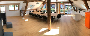 Denkraum “Das Herz“ Raum mit Konferenztisch, Sitzecke und Küche. Panoramabild mit Blick auf Balkon.