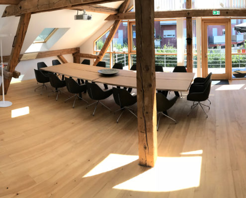 Denkraum “Das Herz“ Raum mit Konferenztisch, Sitzecke und Küche. Panoramabild mit Blick auf Balkon.