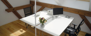 Denkraum Schreibtische mit Blumen und PCs.