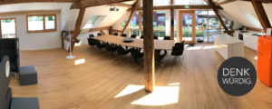 Denkraum “Das Herz“ Raum mit Konferenztisch, Sitzecke und Küche. Panoramabild mit Blick auf Balkon.