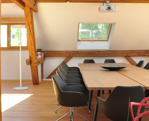 Denkraum “Das Herz“ Raum mit Konferenztisch, Sitzecke und Küche. Blick aus der Küche auf den Konferenztisch