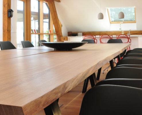 Denkraum “Das Herz“ Raum mit Konferenztisch, Sitzecke und Küche. Blick von Tisch auf Küche.