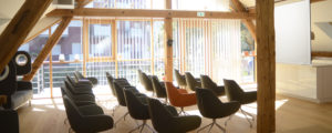Denkraum “Das Herz“ Raum mit Konferenztisch, Sitzecke und Küche. Bestuhlung vor Leinwand.